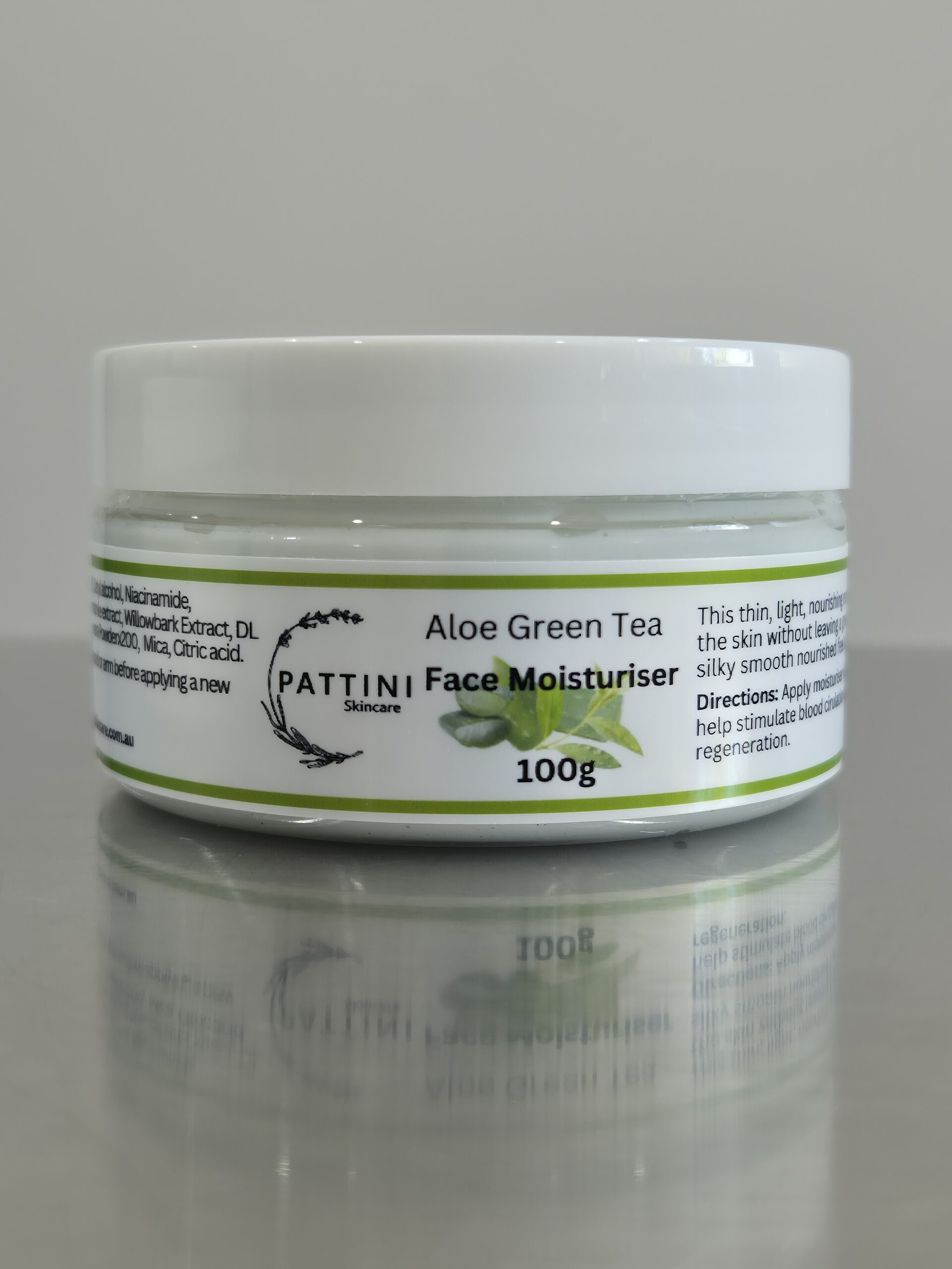 A white jar of Pattini Skincare Aloe Green Tea Face Moisturiser with a green-themed label featuring aloe and tea leaves, placed on a reflective surface.