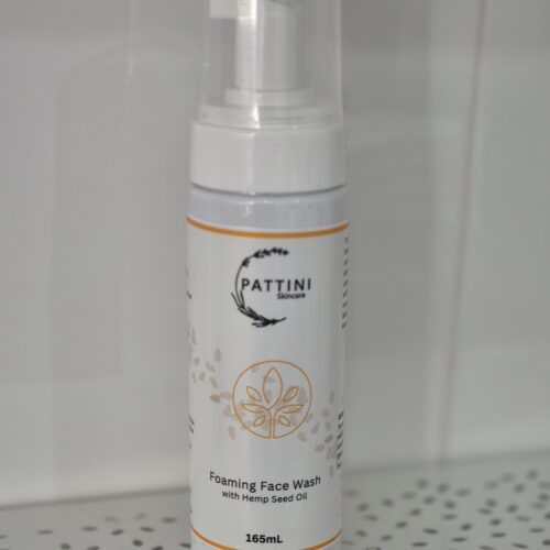 A white pump bottle of Pattini Skincare Foaming Face Wash with Hemp Seed Oil, placed on a perforated shelf against a tiled background.
