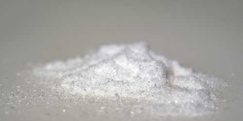A small mound of fine white crystalline powder on a smooth, light-colored surface.