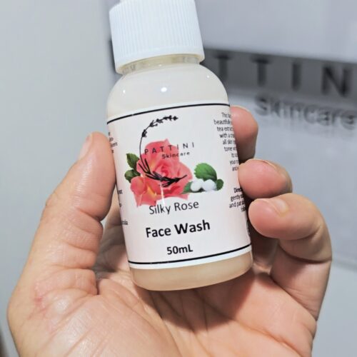A hand holding a small pump bottle labeled Silky Rose Face Wash 50mL from Pattini Skincare.